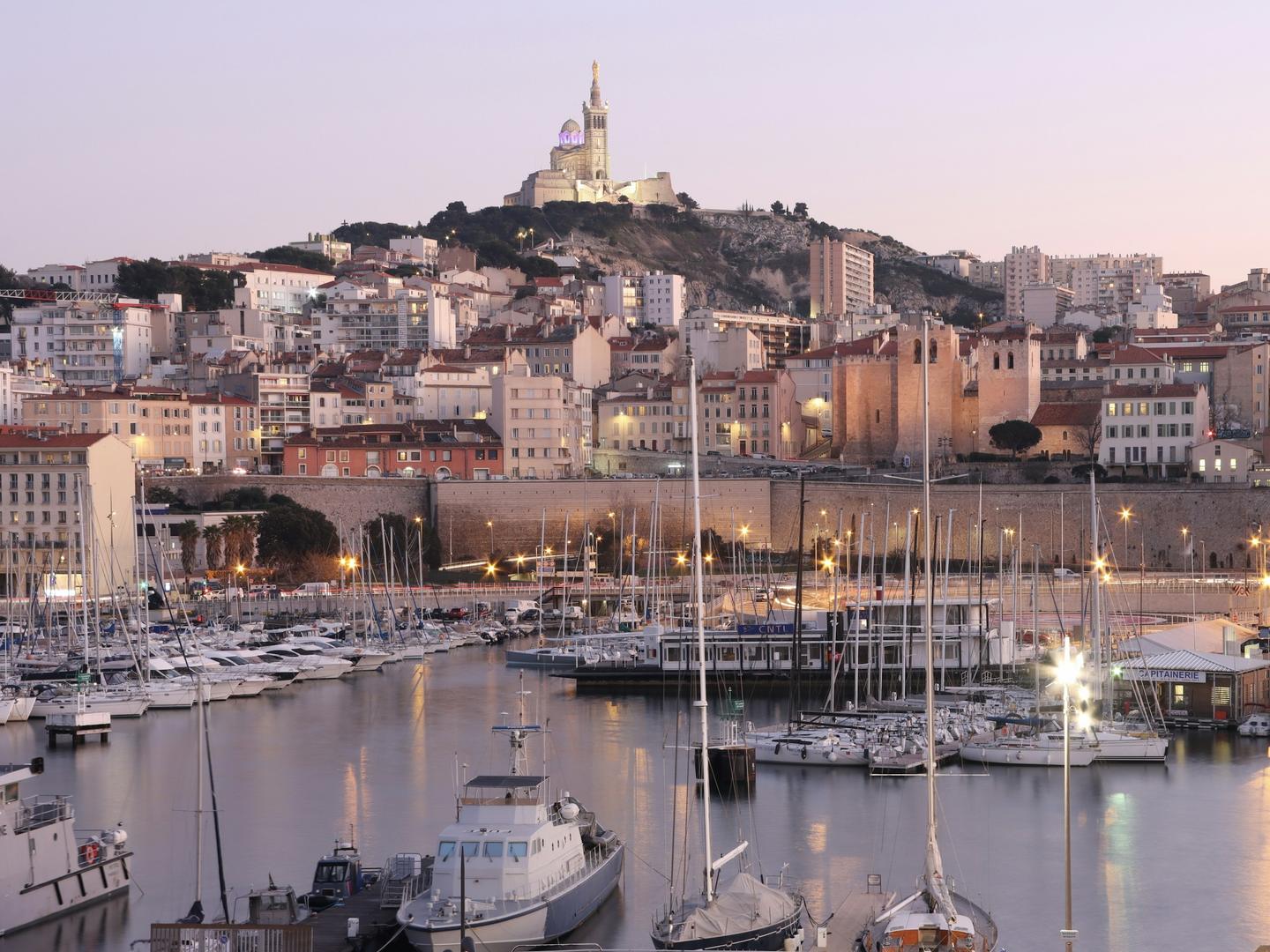 Старый порт Марселя в сумерках, над ним Notre-Dame de la Garde